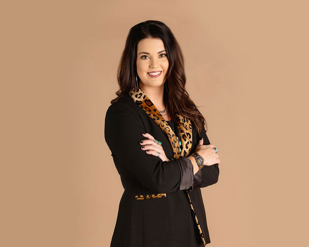 A photo of Shelbi Tidwell posing and wearing a black and cheetah long-sleeved shirt.